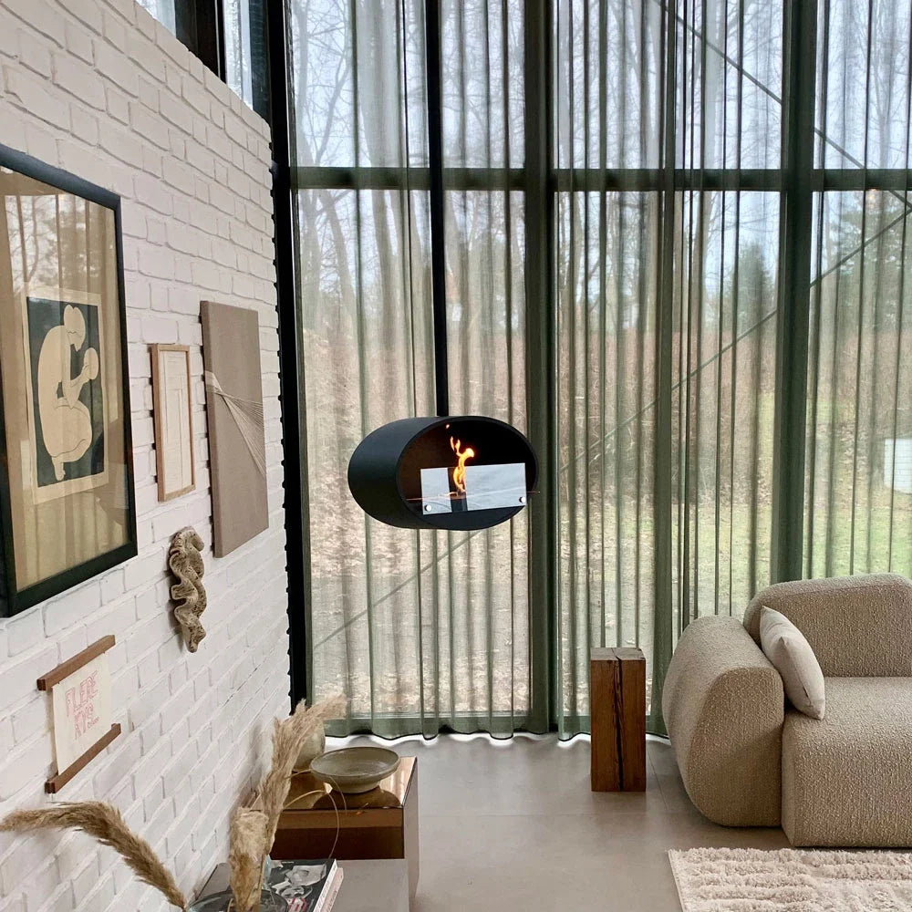 Moderne indrettet daglig stue med loft hængt oval formet sort bio pejs med flammer bag glas plade.