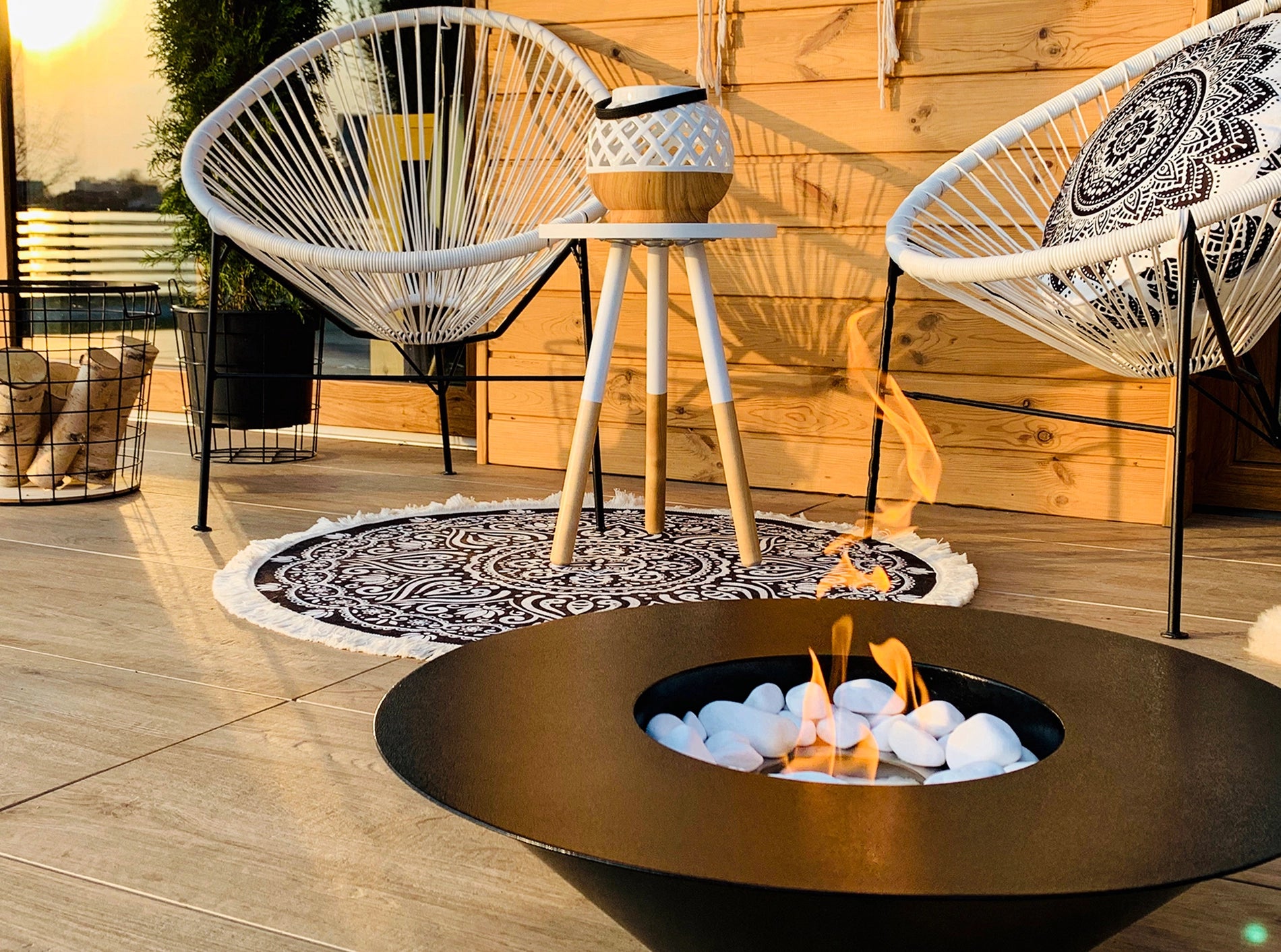 sort elipseformet udendørs biopejs med flotte flammer på terrasse med havemøbler