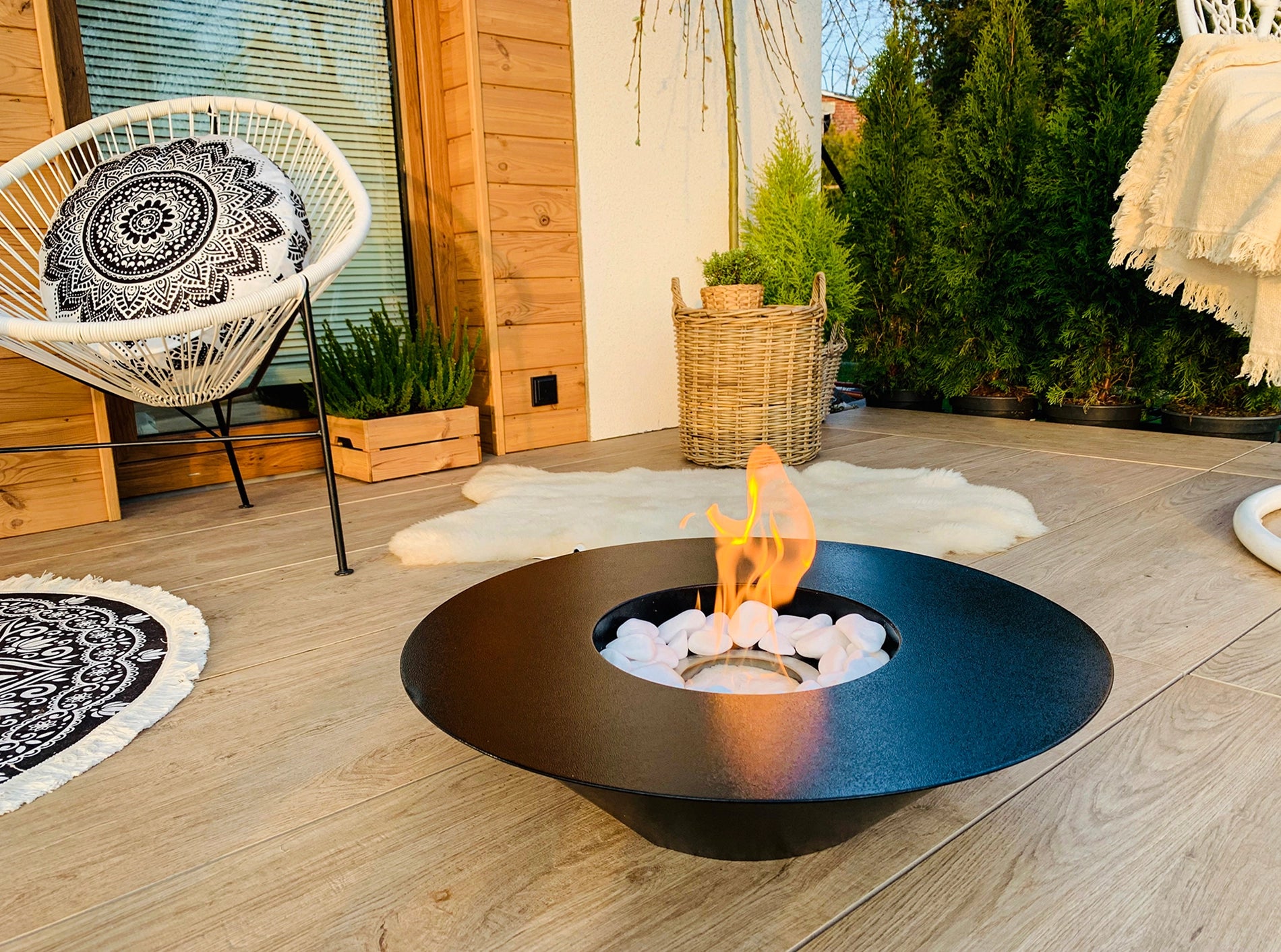 sort elipseformet udendørs biopejs med flotte flammer på træterrasse