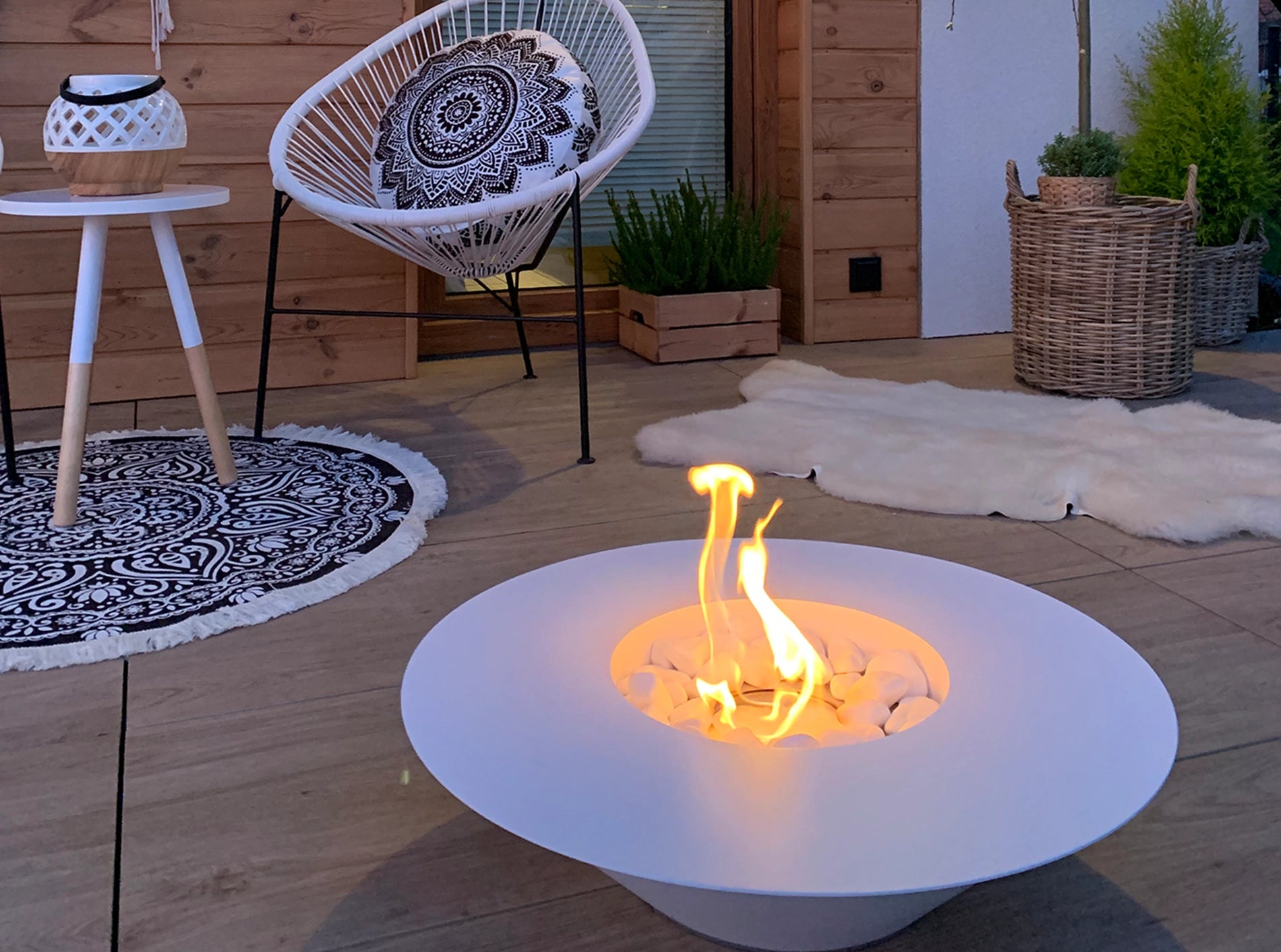 hvid elipseformet udendørs biopejs med flotte flammer på terrasse