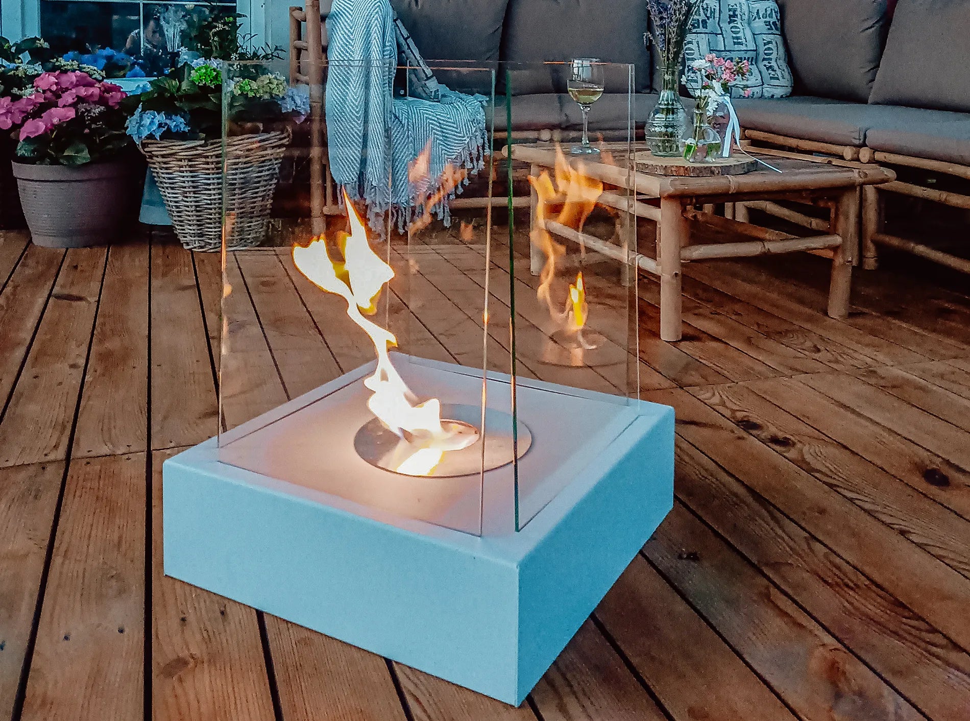 grå bord biopejs med tændte flammer på terrassegulv