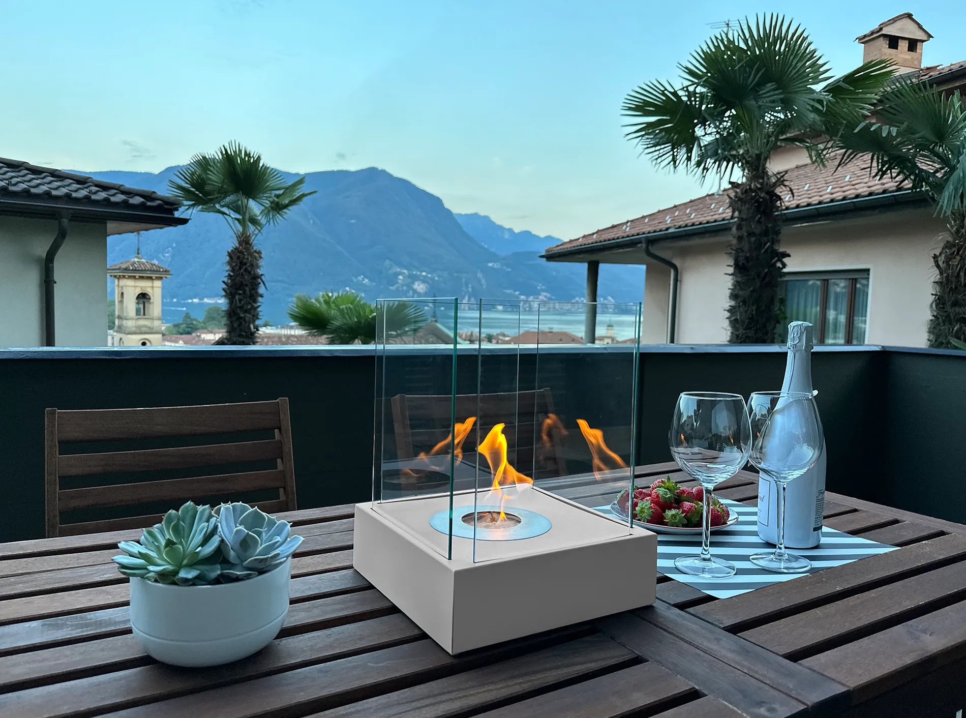 hvid udendørs bord biopejs med sideglas og tændte flammer på havebord