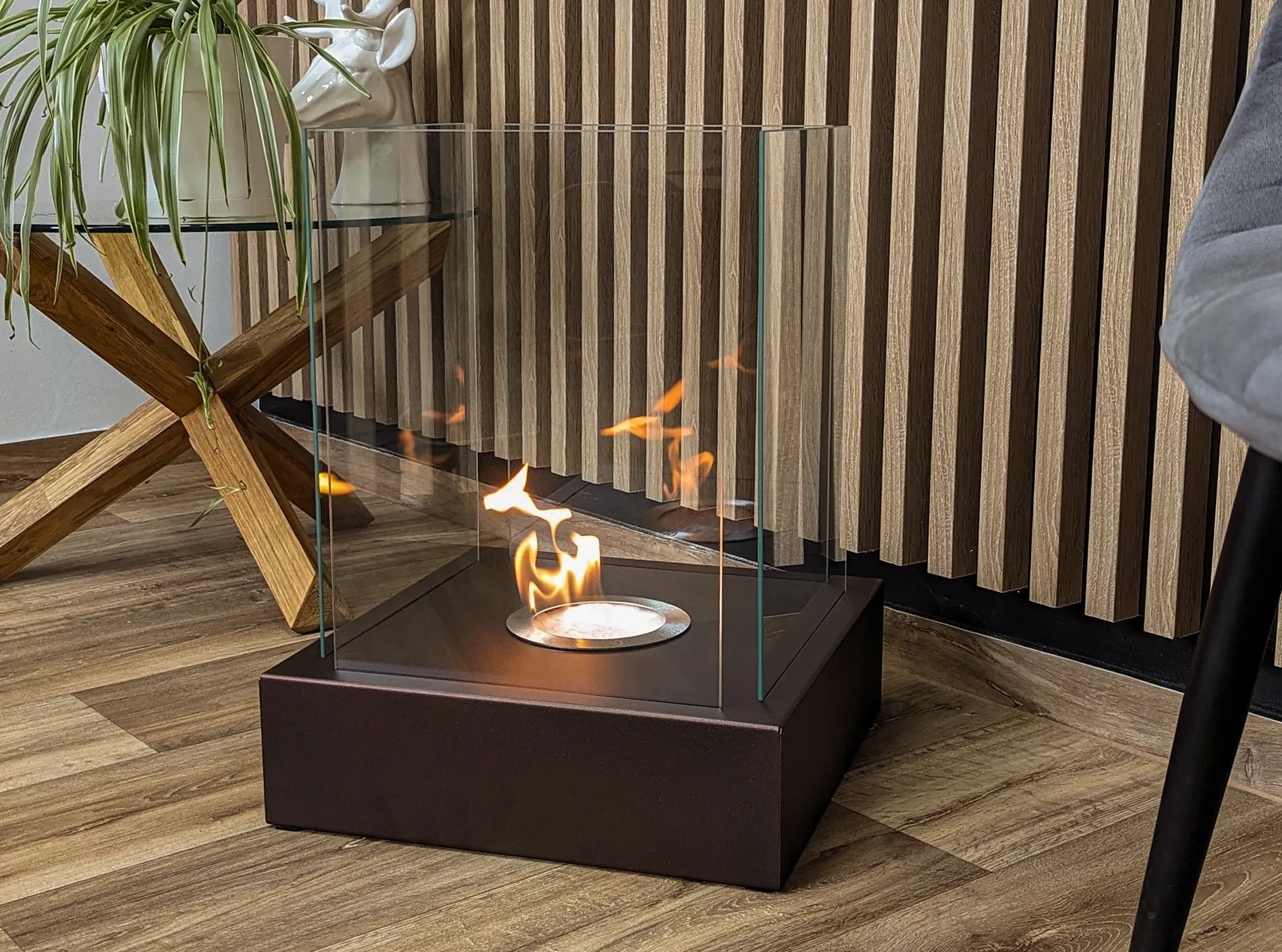 brun fritstående biopejs stående på gulv i stue med flotte flammer
