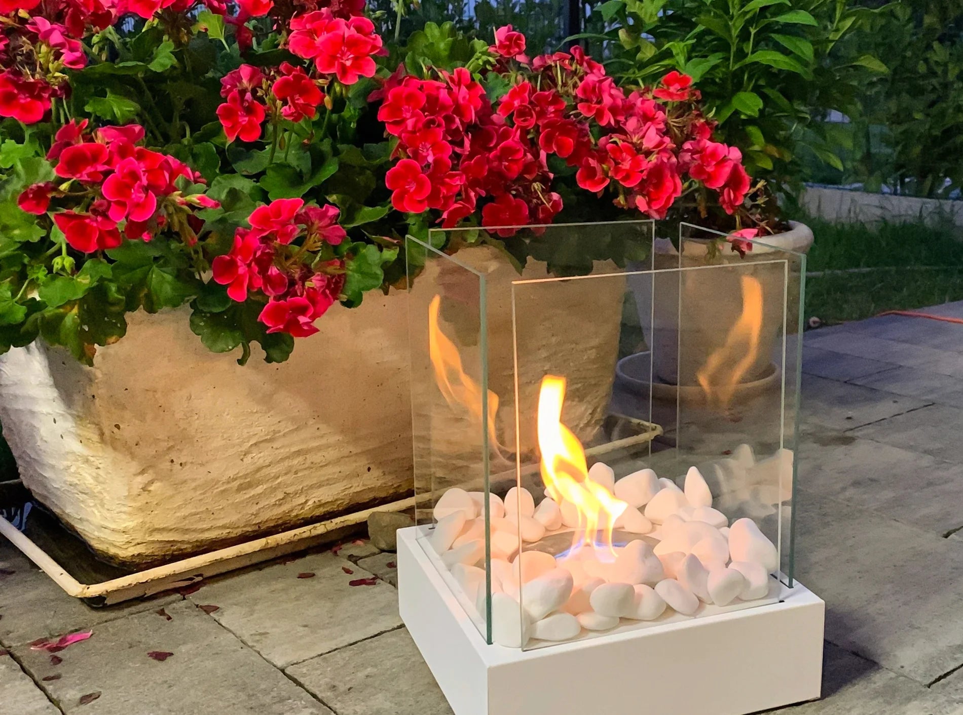 hvid fritstående biopejs på fliser i have med flotte flammer og sideglas