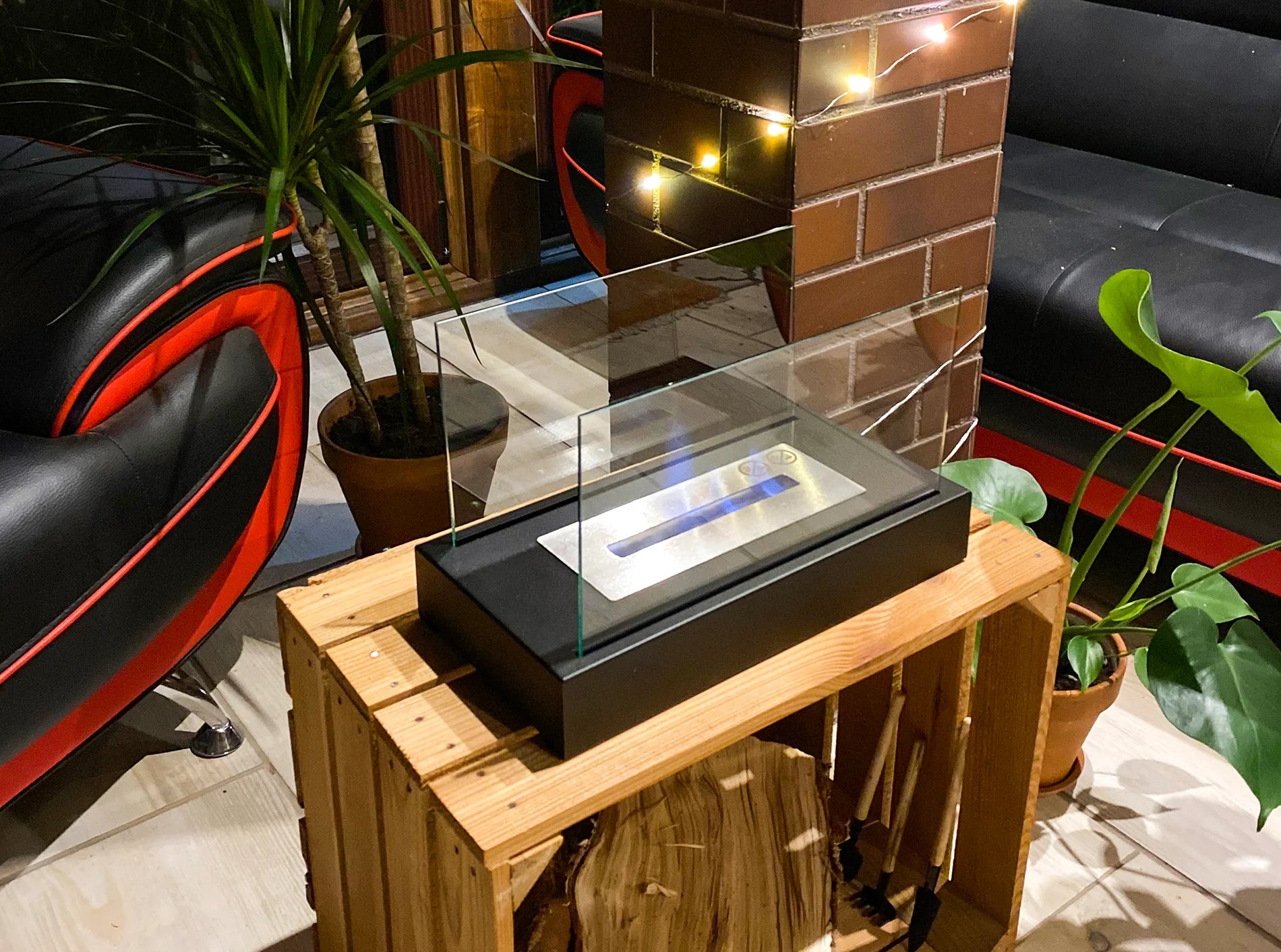 sort bord biopejs med sideglas stående på trækasse i havestue