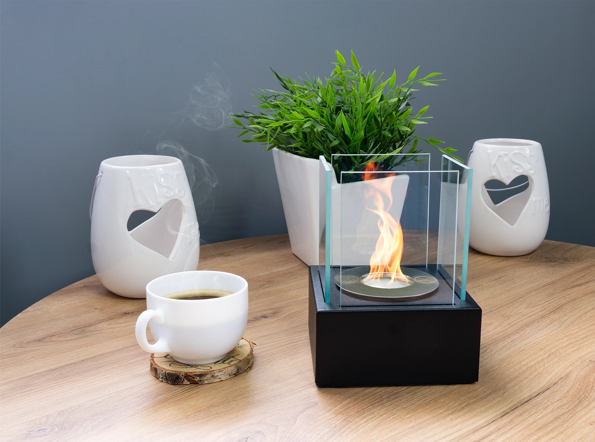sort bord biopejs med sideglas og tændte flammer på kaffebord