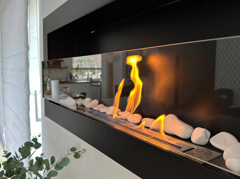 sort vægmonteret biopejs med frontglas på stuevæg med flammer og pyntesten