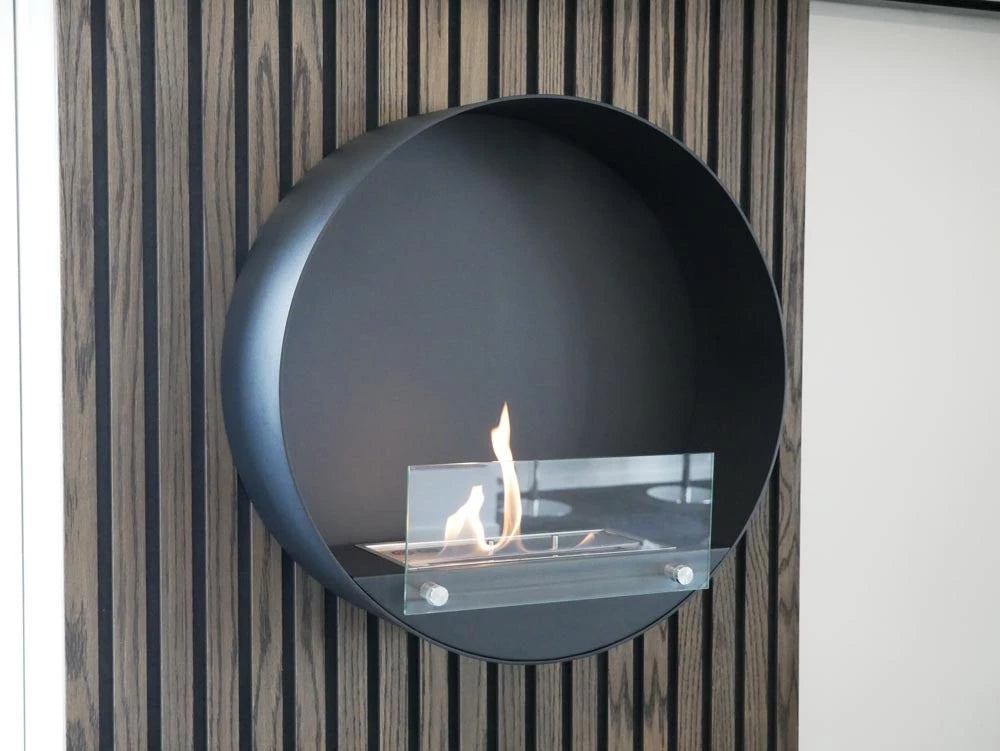 rund sort væghængt biopejs med frontglas og flammer på akustikpanel