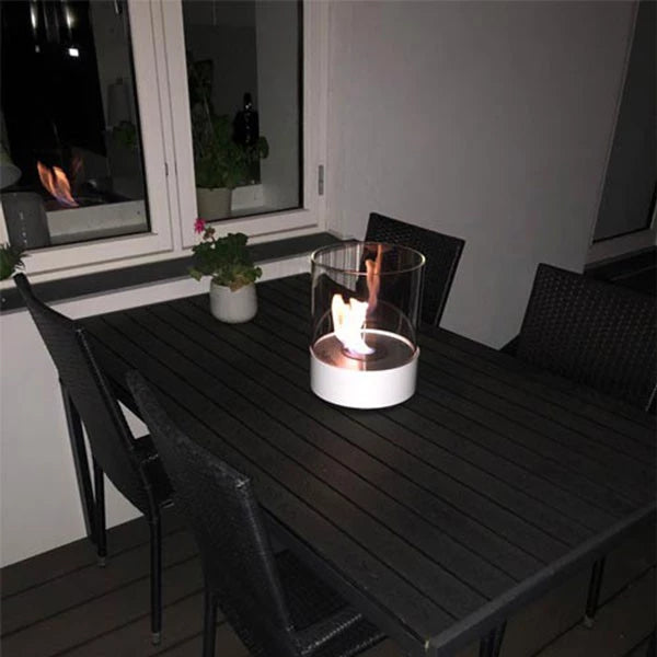 rund hvid bord biopejs med tændte flammer på havebord